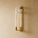 Modern wall sconce with gold frame and white glass on a beige wall