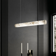 Modern pendant light fixture hanging against a dark wall with a window on the right.