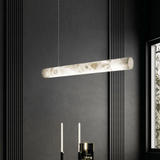 Modern pendant light fixture hanging against a dark wall with a window on the right.