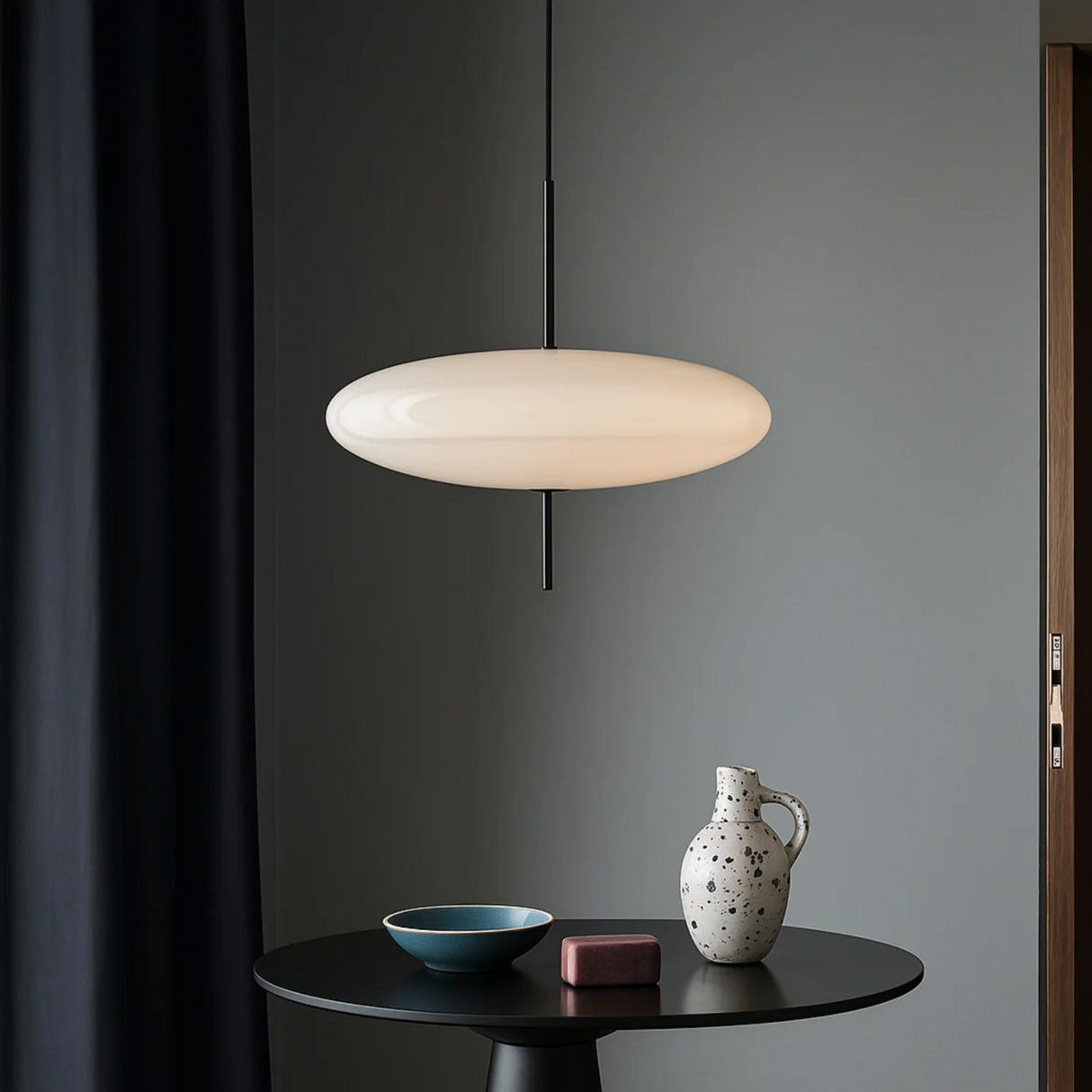 Pendant light fixture hanging above a table with decorative items against a gray wall.