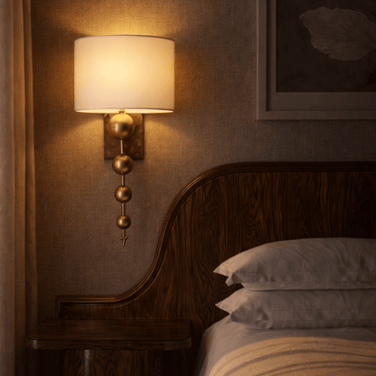 Wall-mounted lamp with a warm glow in a bedroom setting.