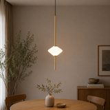 Modern pendant light hanging above a dining table with decor items.