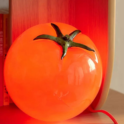 Close-up of the tomato lamp glowing in bright red-orange color on a wooden surface.