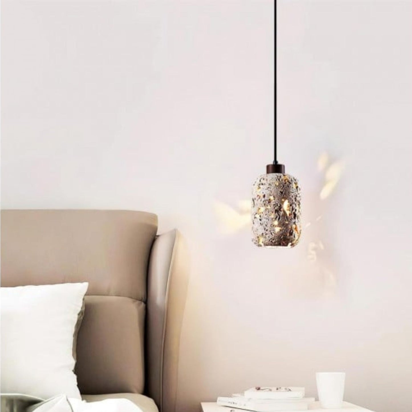 A single pendant light with a decorative, textured glass shade casting soft light on the wall in a cozy bedroom.