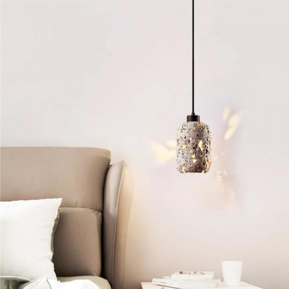 A single pendant light with a decorative, textured glass shade casting soft light on the wall in a cozy bedroom.