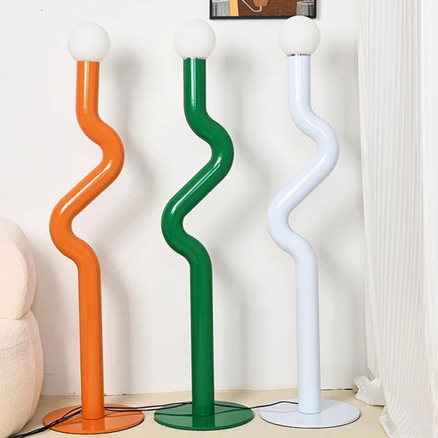 Multiple wavy floor lamps in assorted colors including orange, green, purple, and white standing together in a modern interior setup.