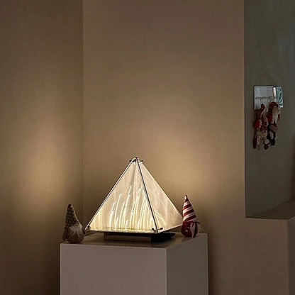 A softly lit cone-shaped lamp placed against a beige wall, creating a warm ambient glow.