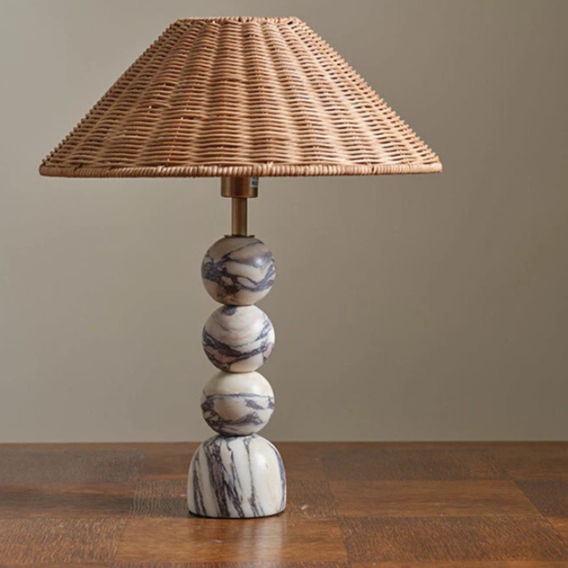 The same lamp on a wooden table in natural lighting, highlighting the marble base and wicker texture.