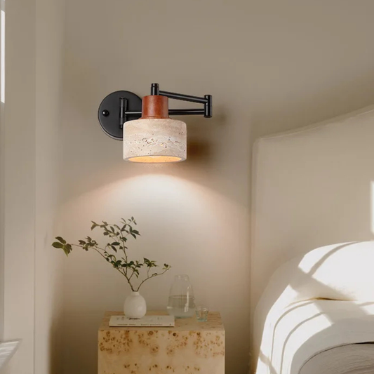 Wall lamp mounted above a bedside table, casting a warm glow over neutral bedding and minimalist decor.