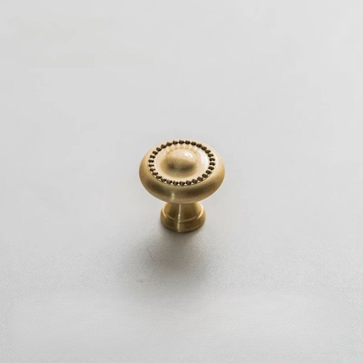 A pair of golden drawer knobs placed on a marble countertop with soft lighting.