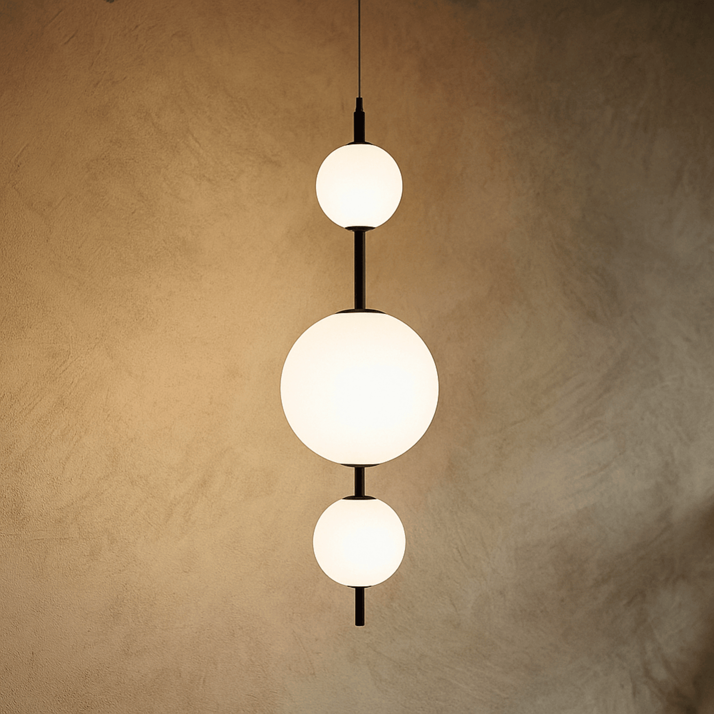 Modern pendant light with three spherical bulbs on a textured beige wall.