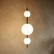 Modern pendant light with three spherical bulbs on a textured beige wall.