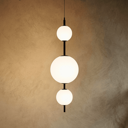 Modern pendant light with three spherical bulbs on a textured beige wall.