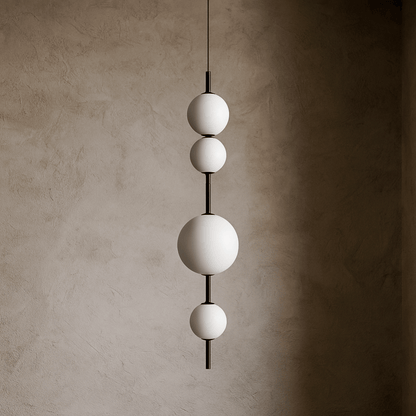 Modern pendant light with three spherical shades against a textured wall.