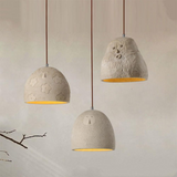 Three concrete pendant lights with floral patterns on a neutral background