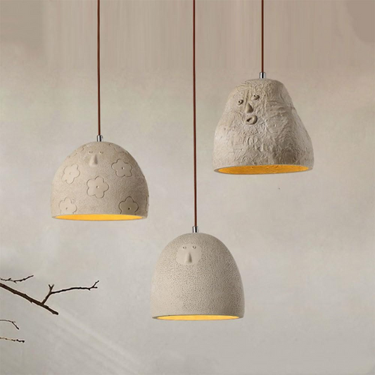 Three concrete pendant lights with floral patterns on a neutral background
