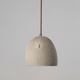 Textured pendant light with a face design on a plain background
