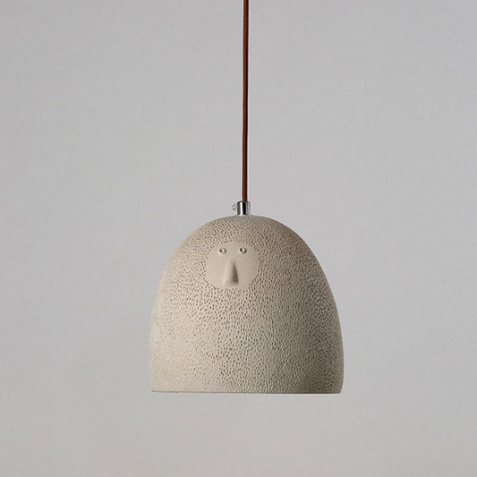 Textured pendant light with a face design on a plain background