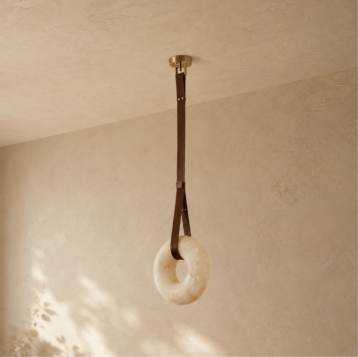Decorative ring hanging from a strap against a beige wall