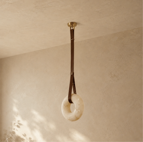 Decorative ring hanging from a strap against a beige wall