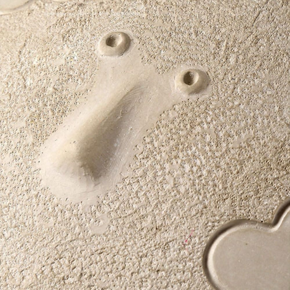 Close-up of a textured beige surface with two small holes and a shadow.