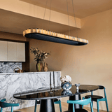 Modern kitchen with a black dining table and chairs, marble countertop, and pendant light.
