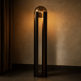 Tall cylindrical floor lamp with a glass shade against a textured wall.