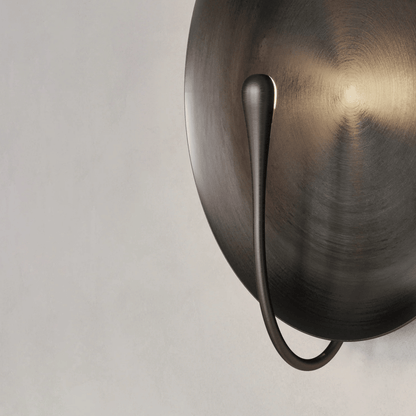 Bronze wall sconce with a single light on a neutral background