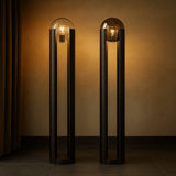 Two modern floor lamps with glass shades against a warm-toned wall.