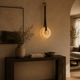 Modern interior with a hanging light fixture, vase, books, and bowl on a wooden console table.