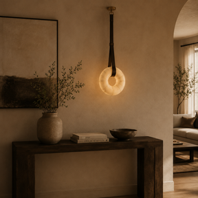 Modern interior with a hanging light fixture, vase, books, and bowl on a wooden console table.