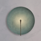 Round wall light fixture with a metallic arm on a gray background