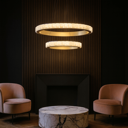 Modern chandelier hanging above a marble table with two armchairs in a dimly lit room.