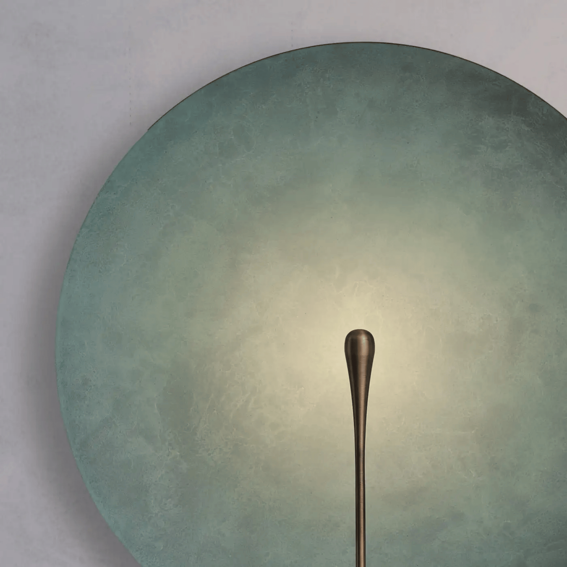 Bronze spoon on a textured green plate with a gradient background