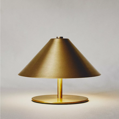 Gold table lamp with a cone-shaped shade on a light gray background