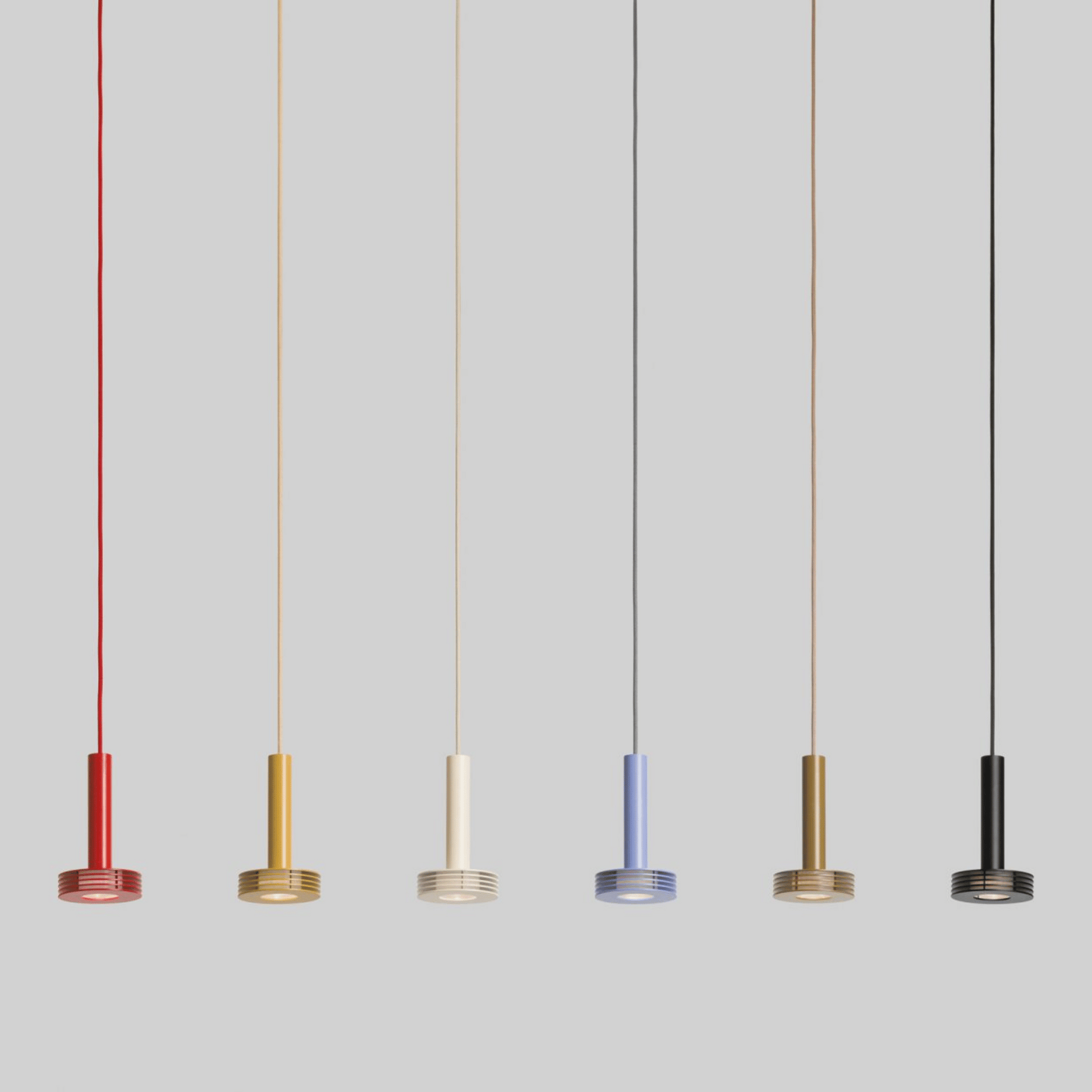 Five pendant lights in different colors hanging against a gray background