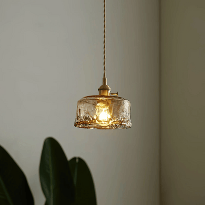 Glass pendant light with gold fixture on a neutral background