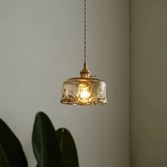 Glass pendant light with gold fixture on a neutral background