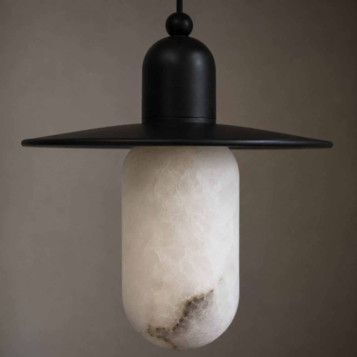 Pendant light with black metal shade and textured white bulb against a neutral background