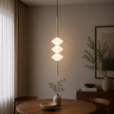 Modern pendant light fixture in a room with a table and decor items.