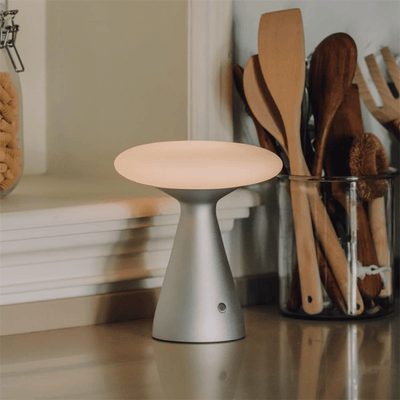 Small round lamp on a kitchen counter with wooden utensils in the background