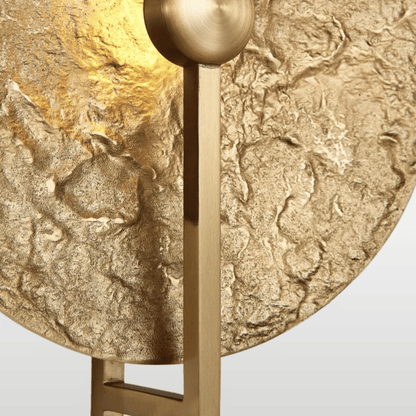 Gold textured round object with a central fixture on a light gray background