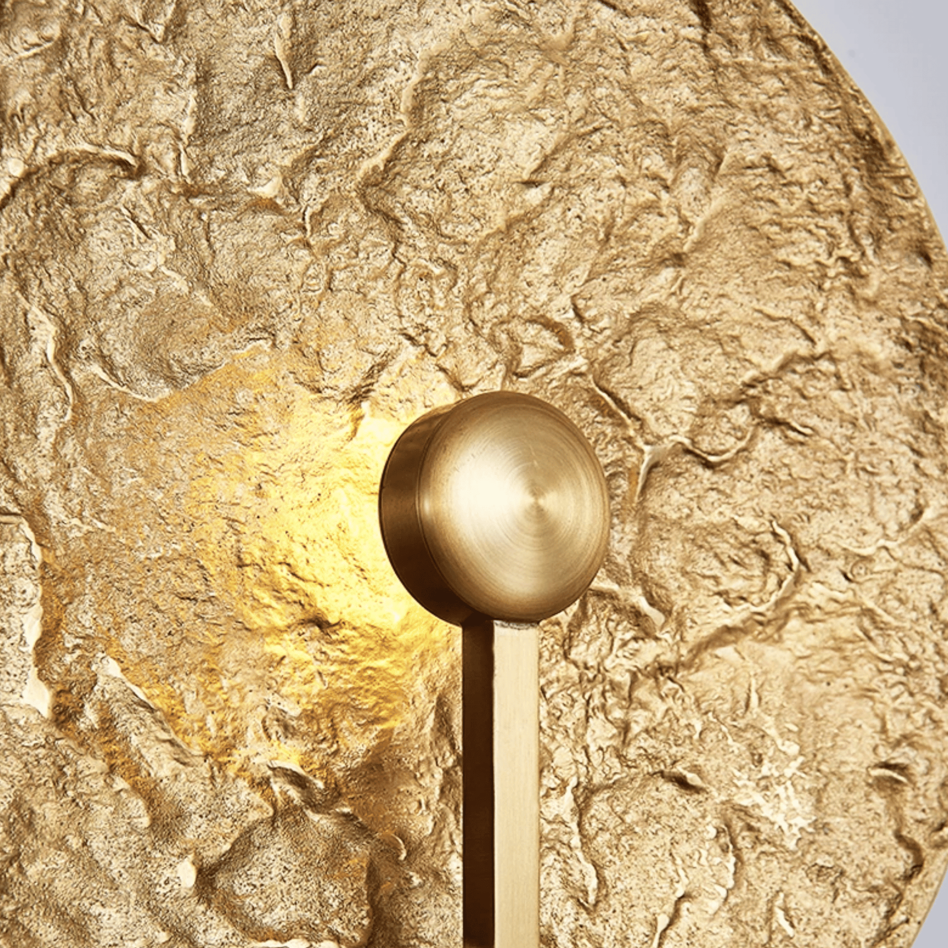 Gold wall sconce mounted on a textured gold wall
