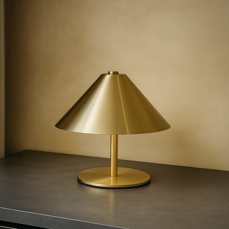 Gold table lamp on a dark surface with a beige wall background