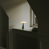 Small table lamp on a windowsill with a neutral background