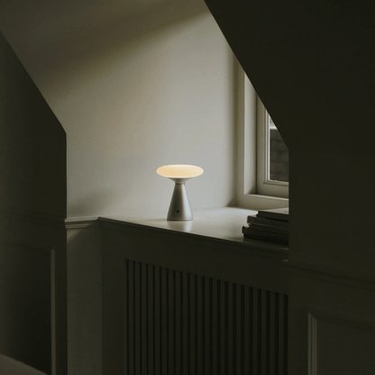Small table lamp on a windowsill with a neutral background