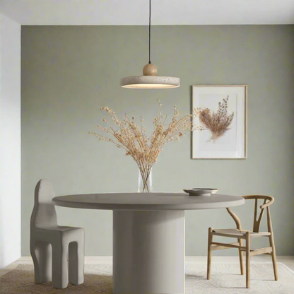 Modern dining area with a round table and chairs against a neutral wall.