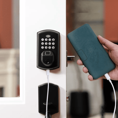 Smart lock on a door with a hand holding a smartphone