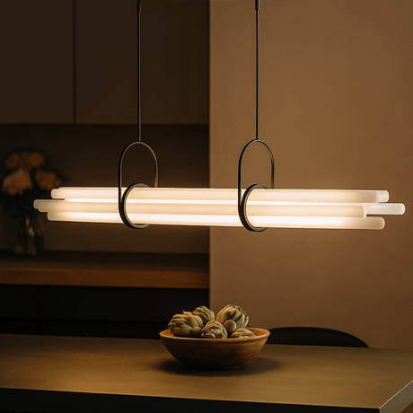 Modern pendant light fixture with a bowl of fruit on a table in a dimly lit room.