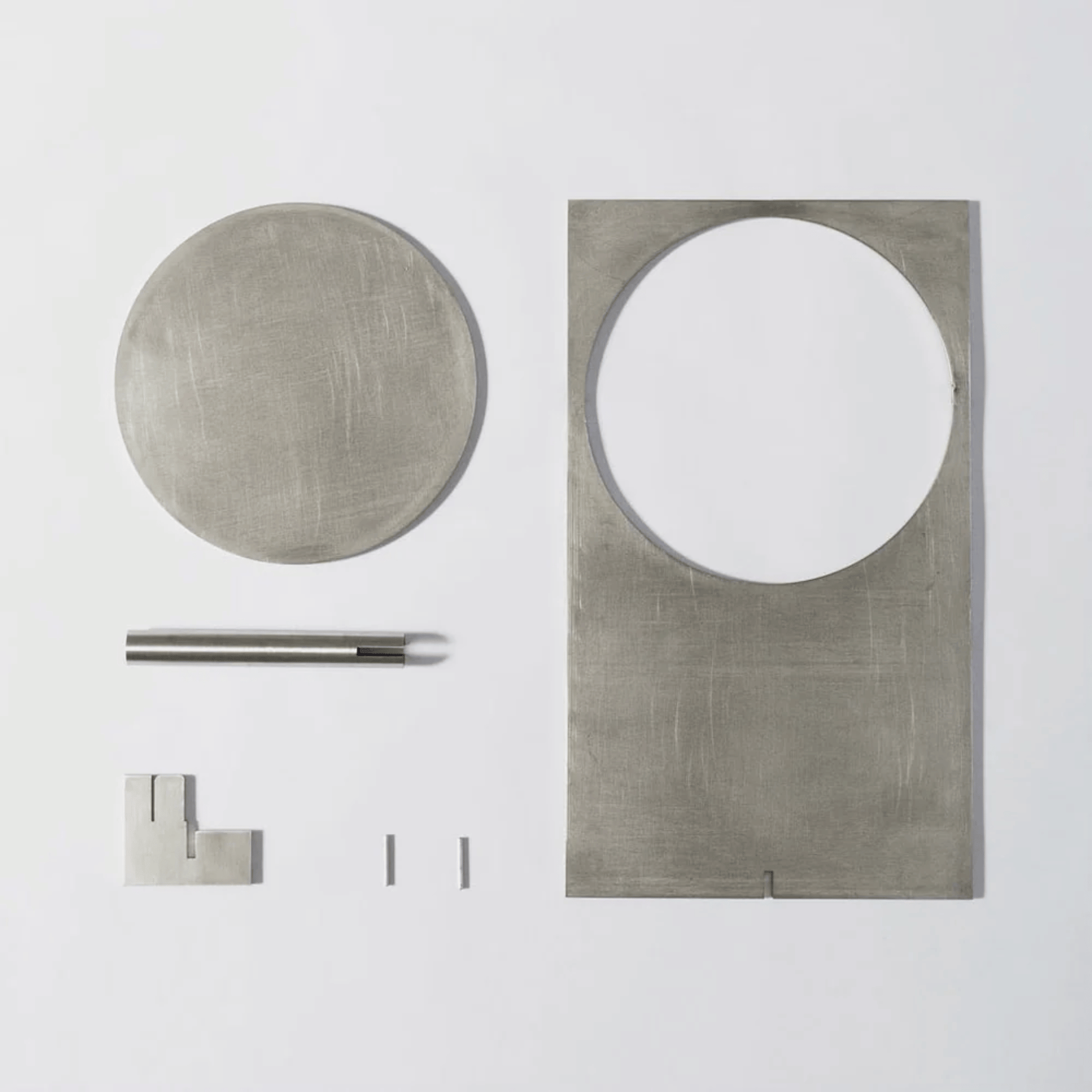 Set of metallic bathroom fixtures including a round mirror, rectangular mirror, towel bar, and hooks on a white background.